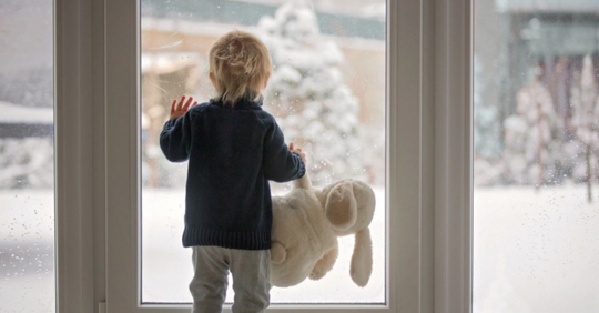 child looking outside at snow